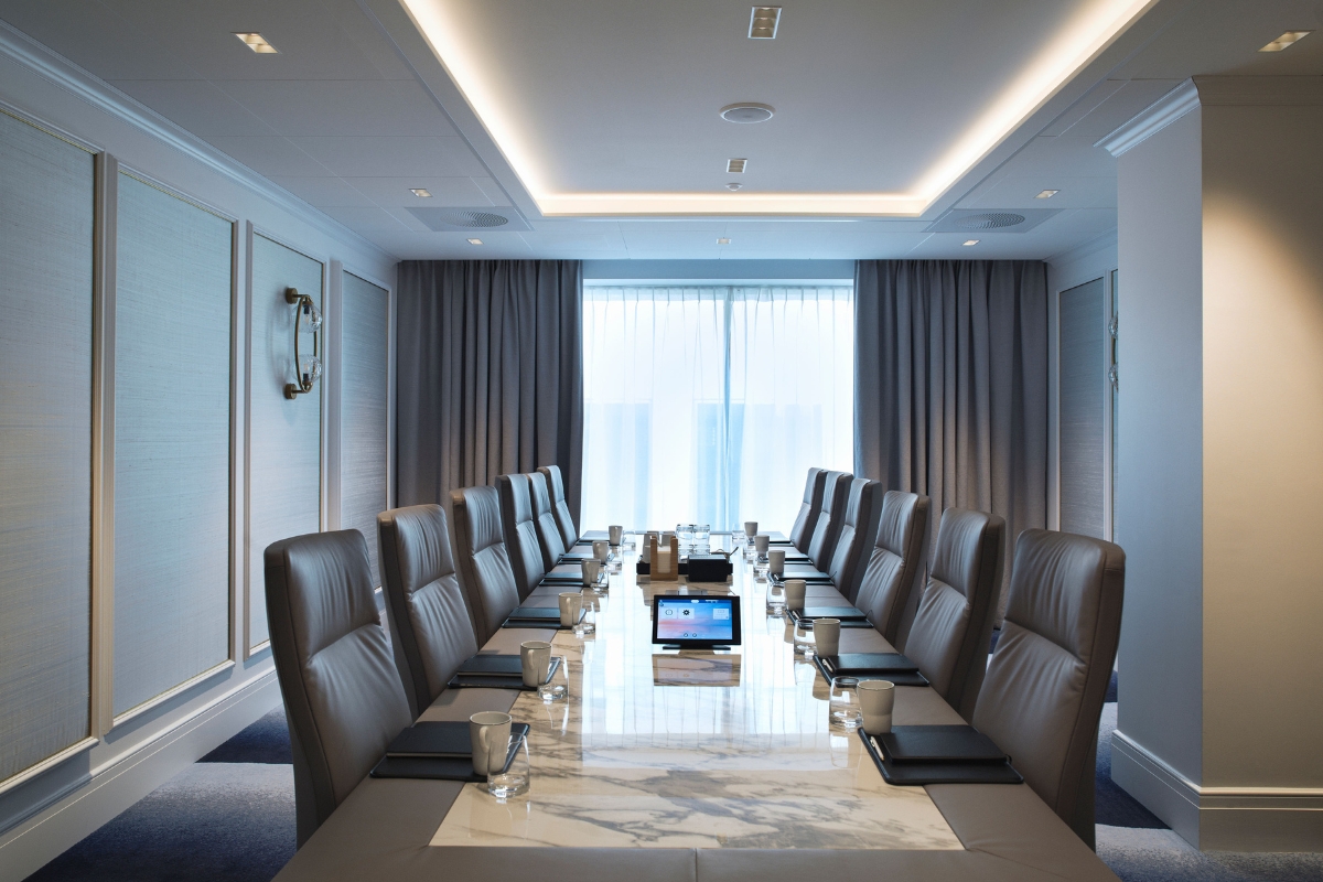 a long conference table with chairs and a tablet on it