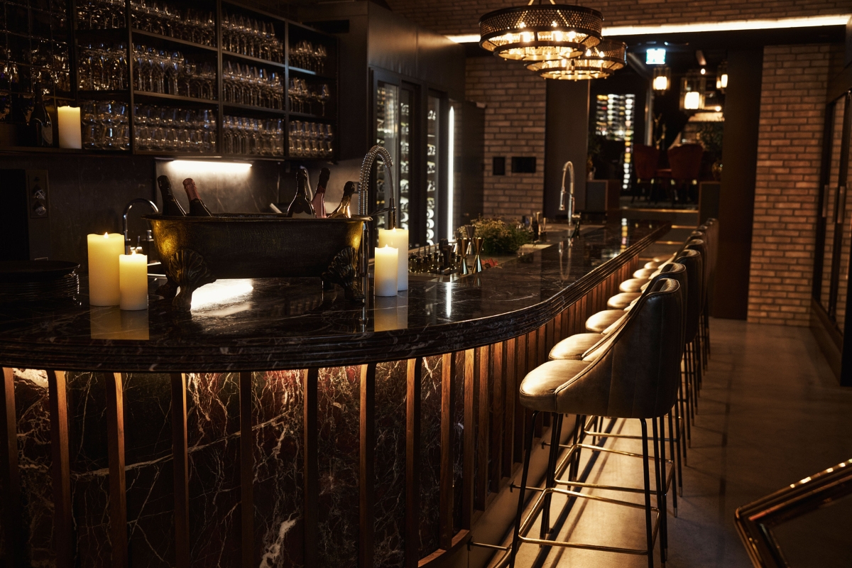 a bar with a black counter and chairs