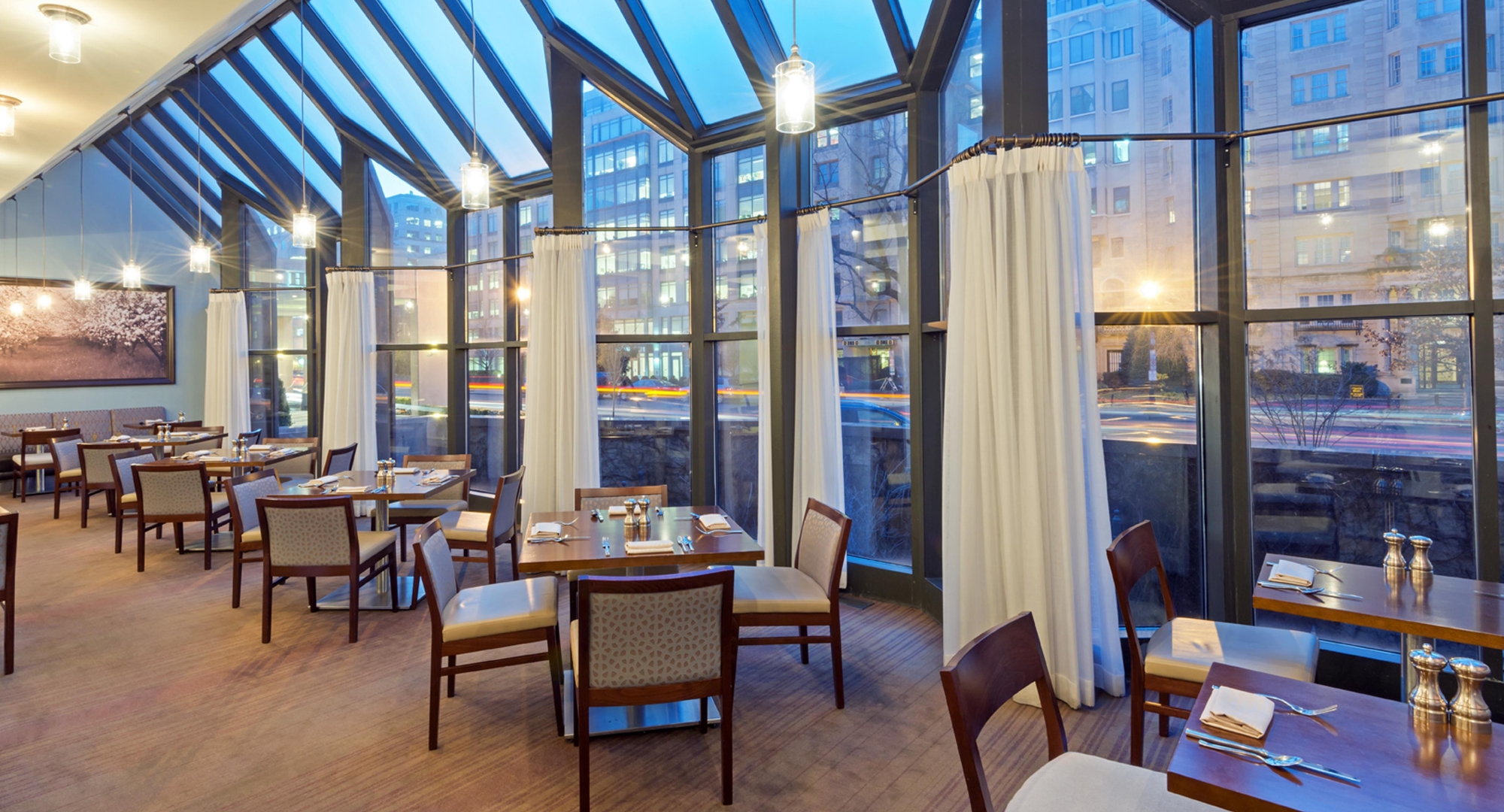 a room with a glass wall and tables and chairs