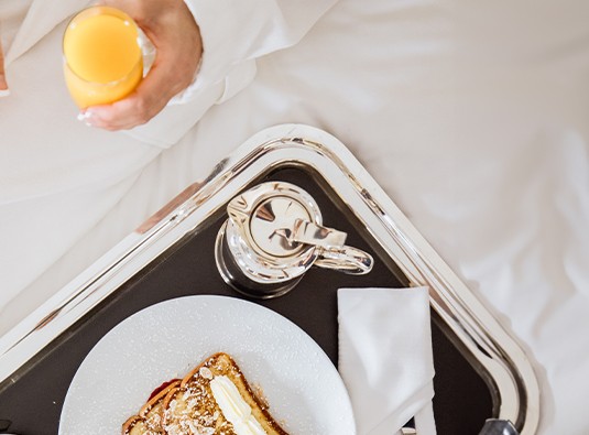 a person holding a glass of juice and a plate of food on a tray