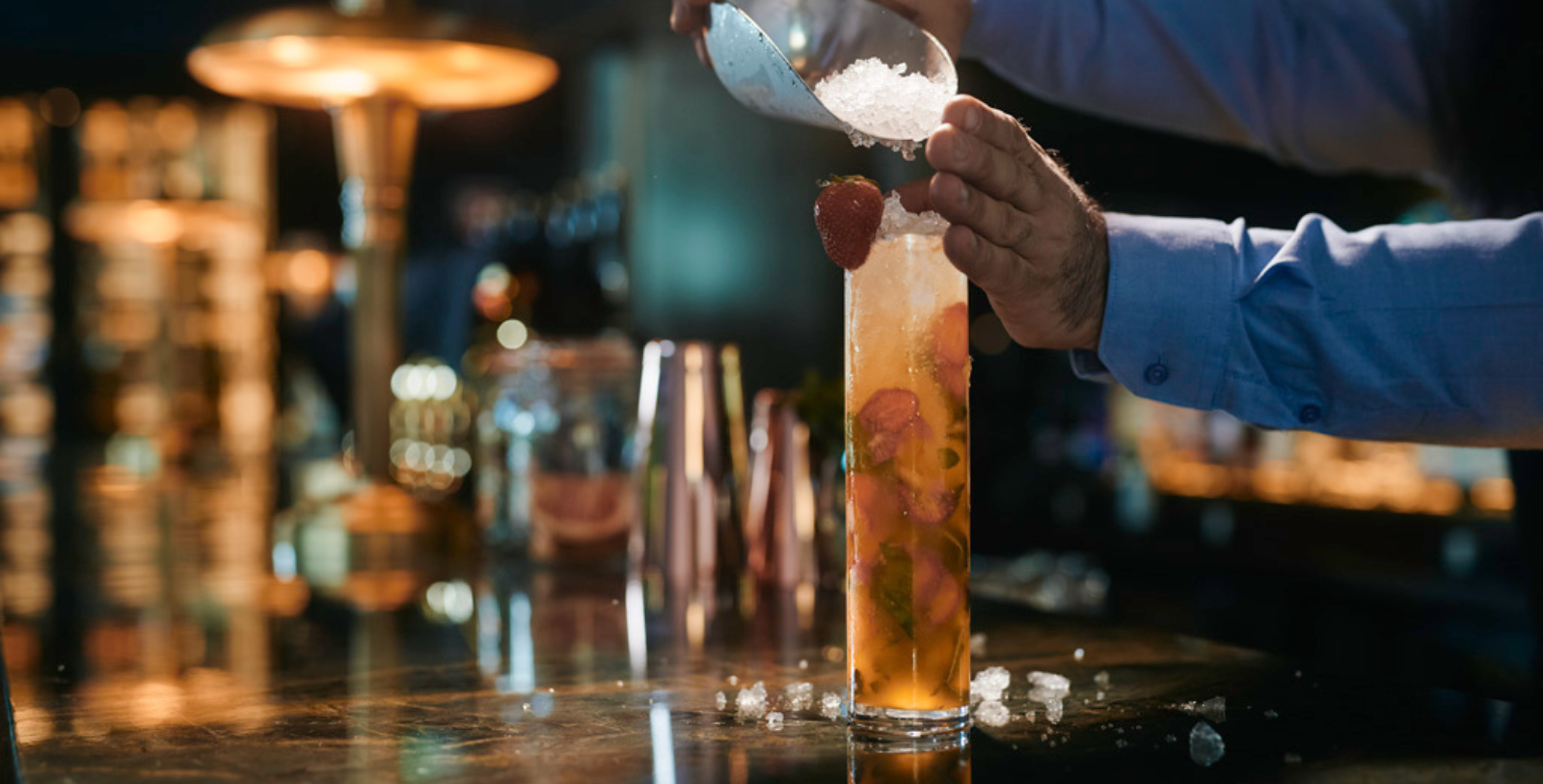 a person pouring a drink into a tall glass