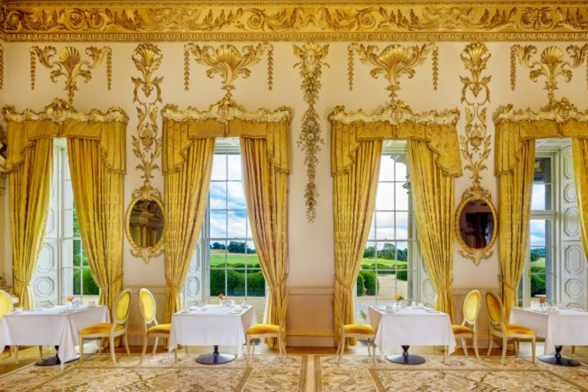 a room with tables and chairs and gold curtains