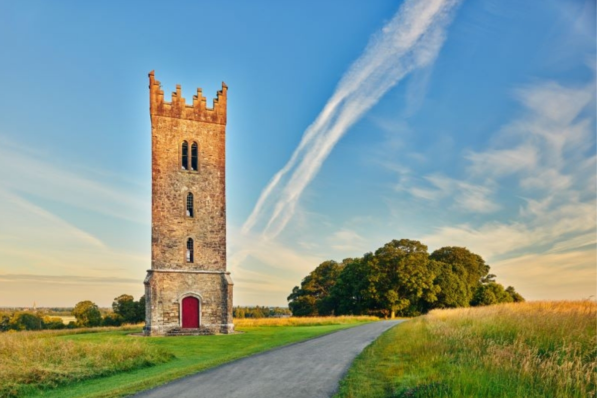 a stone tower with a red door and a road in the middle