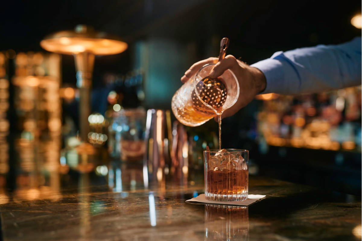 a person pouring a drink into a glass