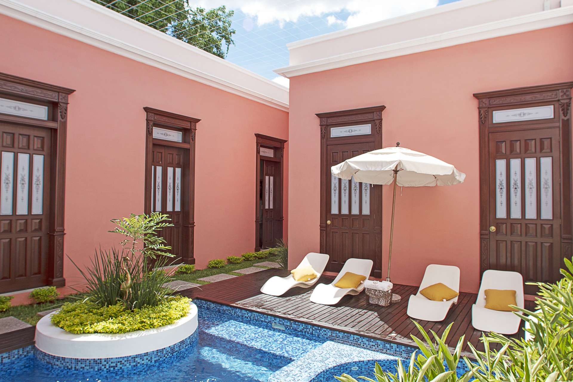 a pink building with chairs and umbrellas
