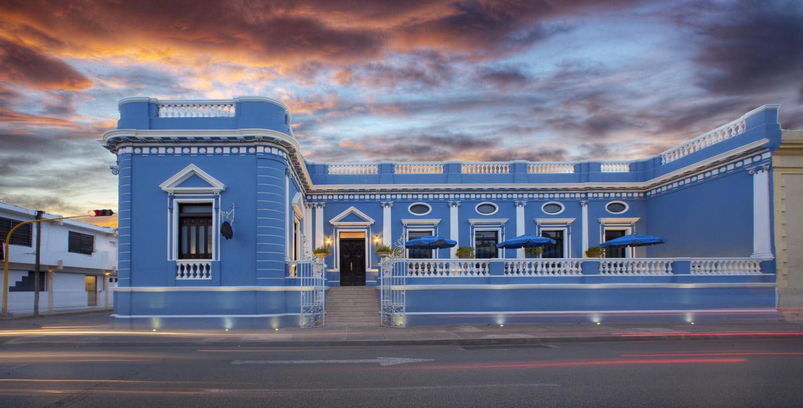 a blue building with a railing and umbrellas