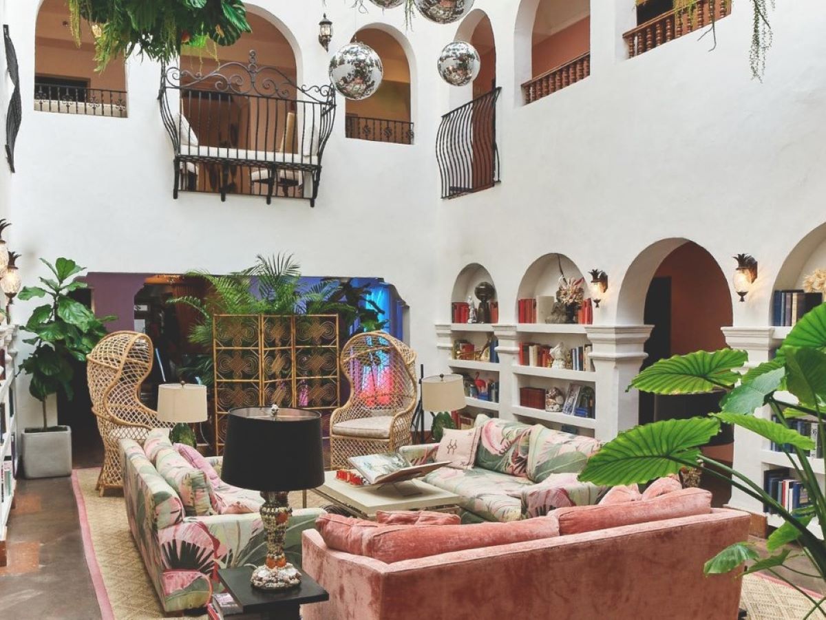 a room with a large white wall and a large white wall with a large pink couch and a black lamp