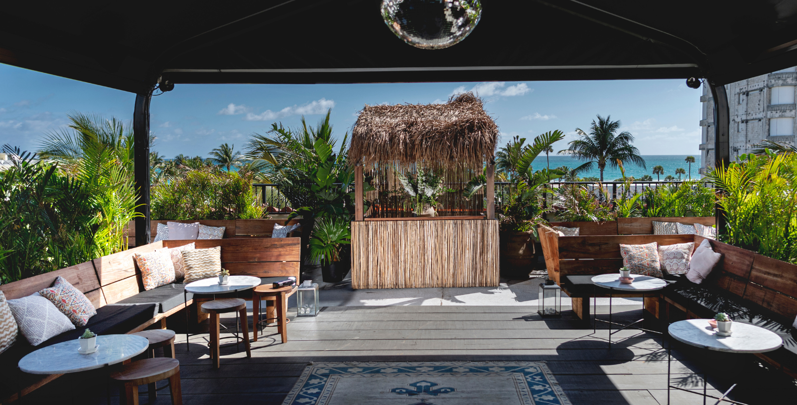 a patio with a straw hut and chairs and a mirror ball