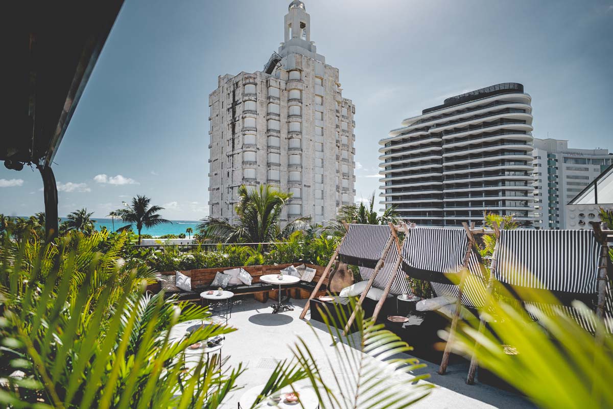 a deck chairs and tables with chairs on a rooftop overlooking a beach
