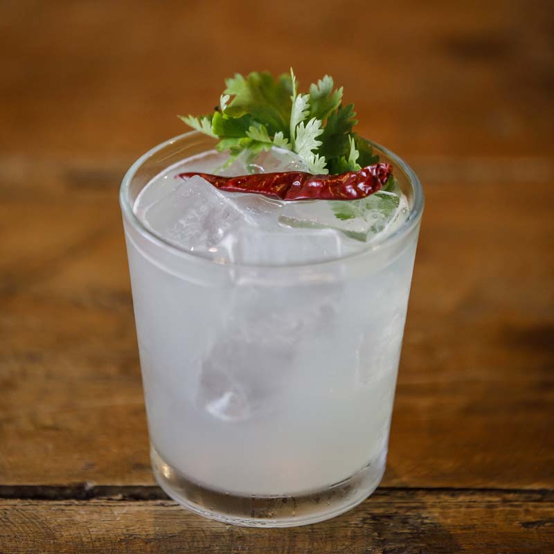 a glass with ice and a red pepper on top