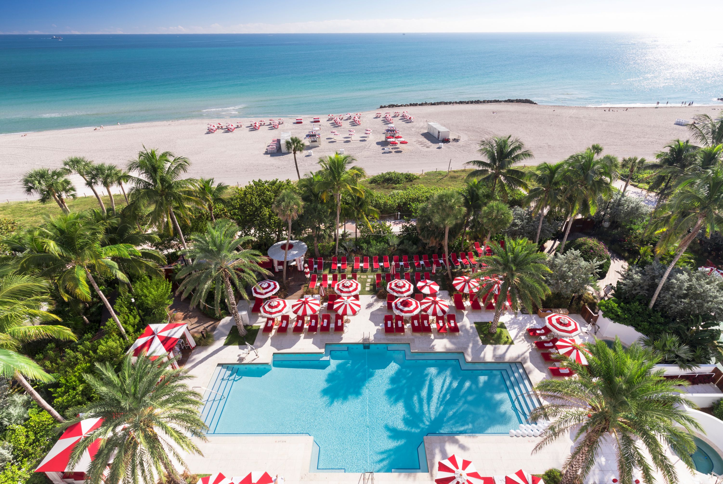 a pool with umbrellas and chairs on a beach