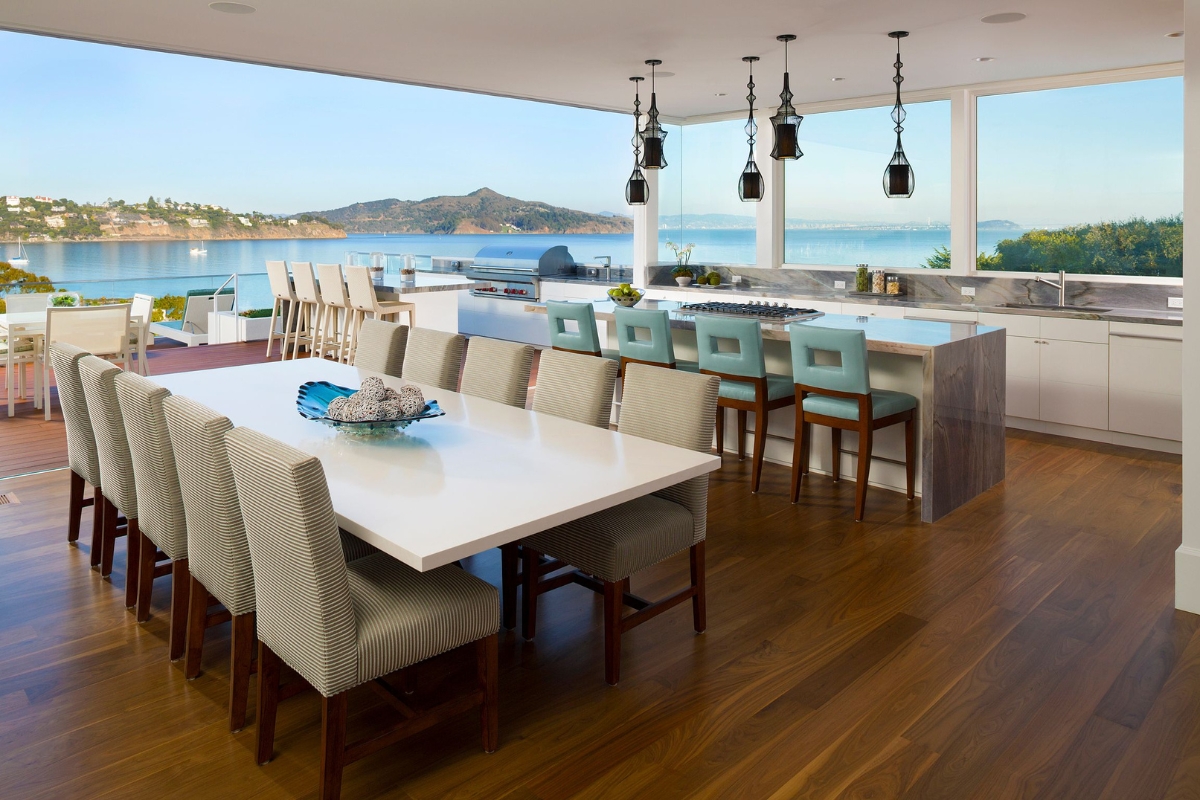 a dining table and chairs in a room with a view of water and mountains