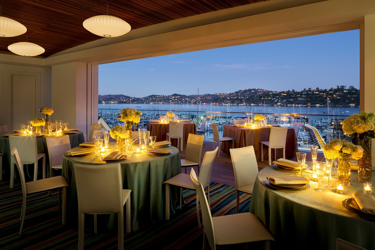 a room with tables and chairs and a view of the water