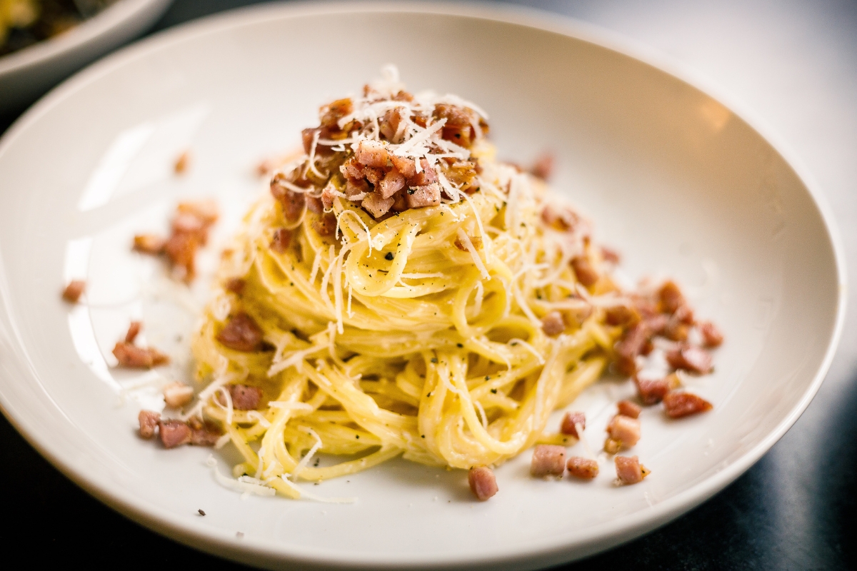 a plate of spaghetti with bacon and cheese