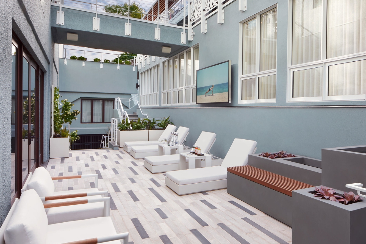 a patio with white chairs and a television on the wall