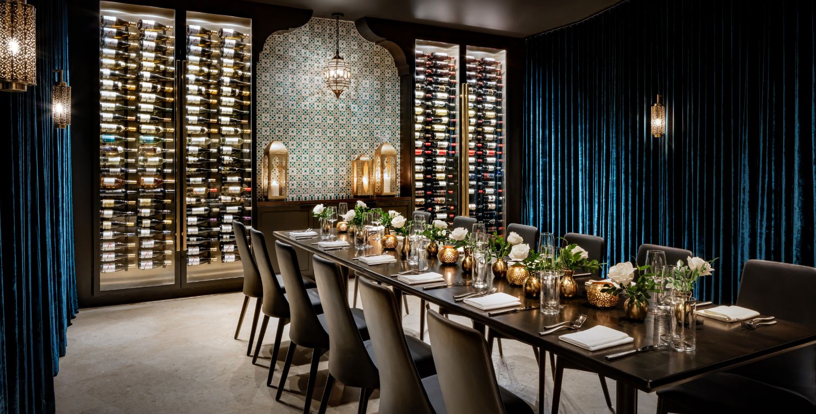 a long table with chairs and wine bottles in a room
