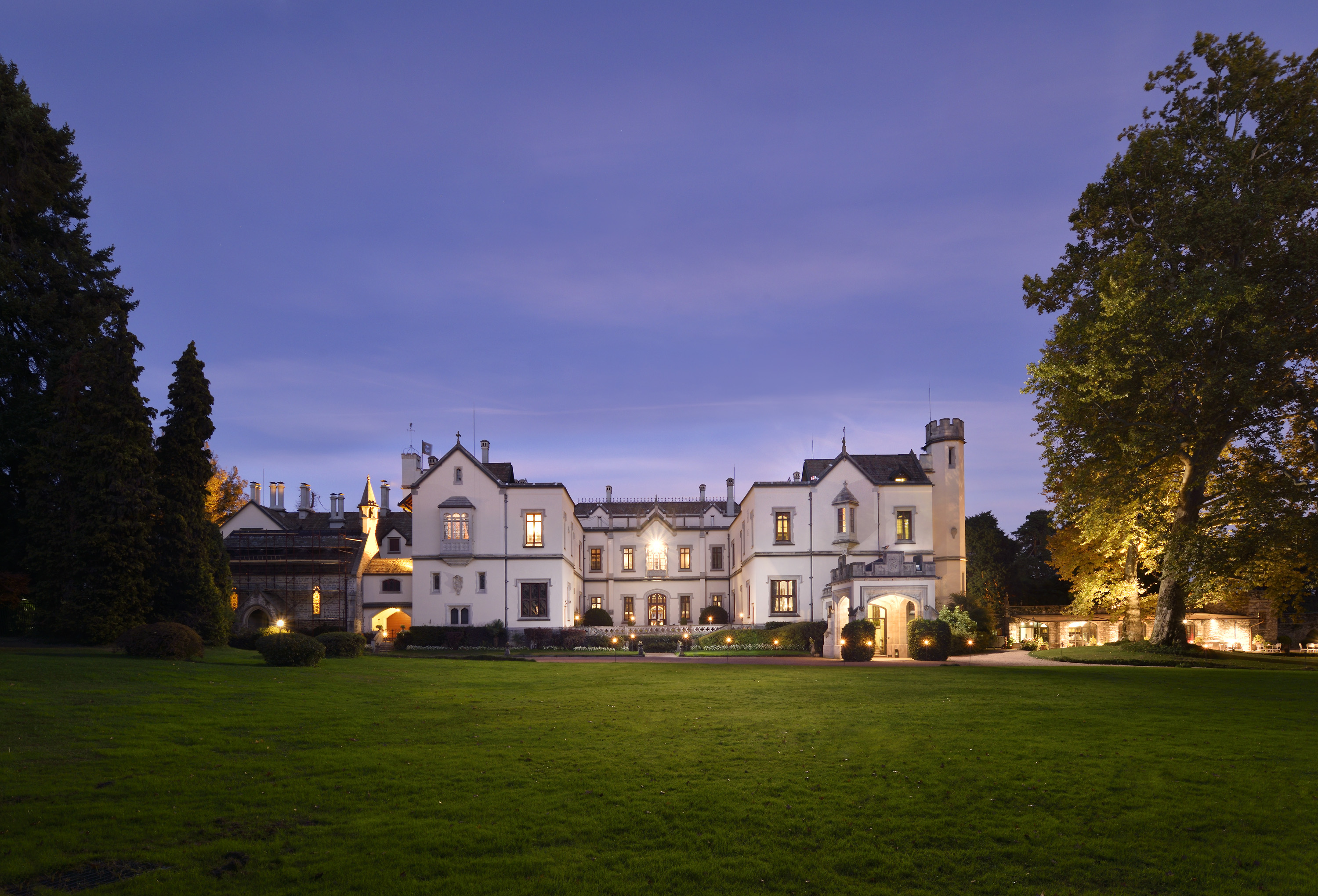 a large white house with a lawn and trees in the background
