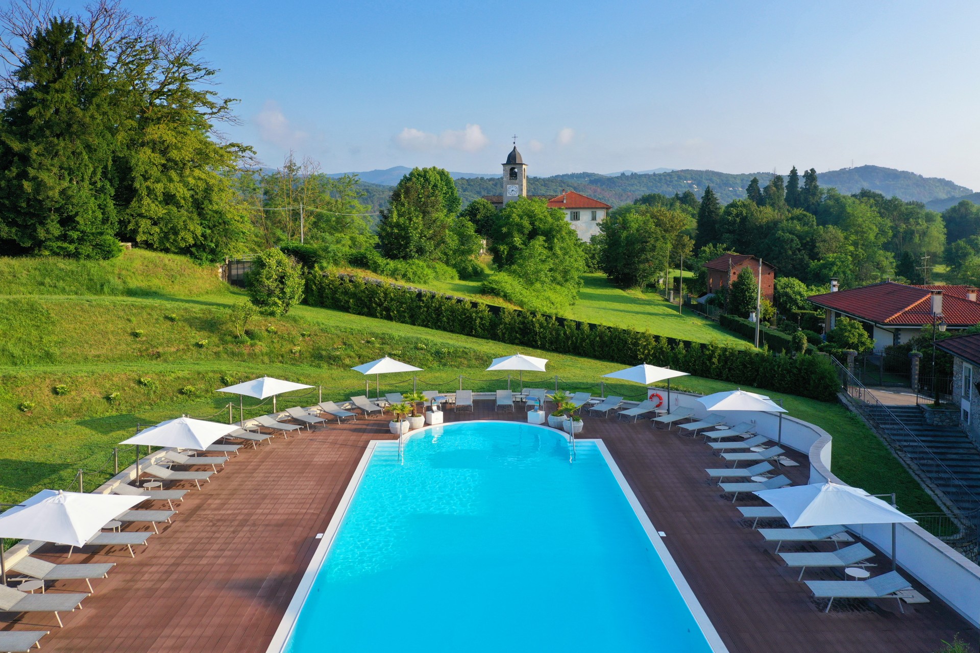 a pool with chairs and umbrellas in a grassy area