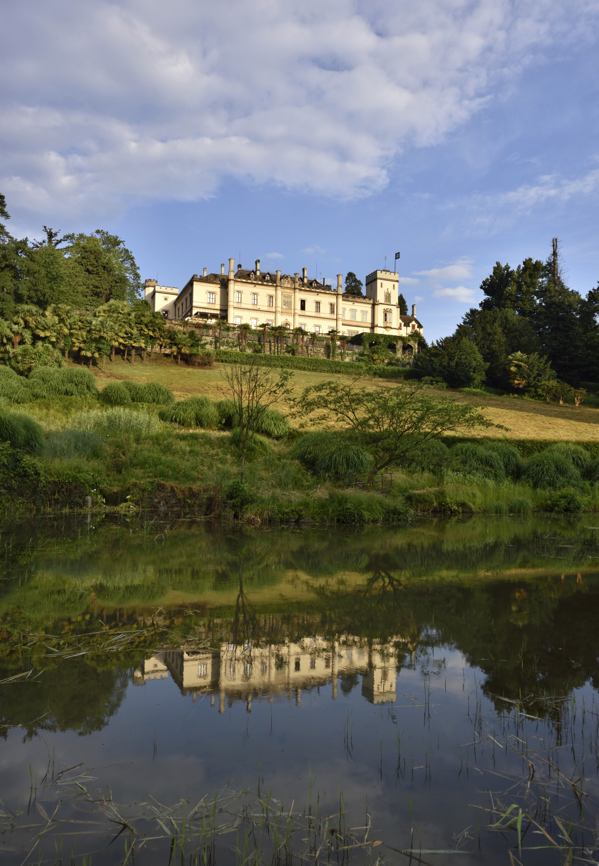 a building on a hill with trees and a body of water