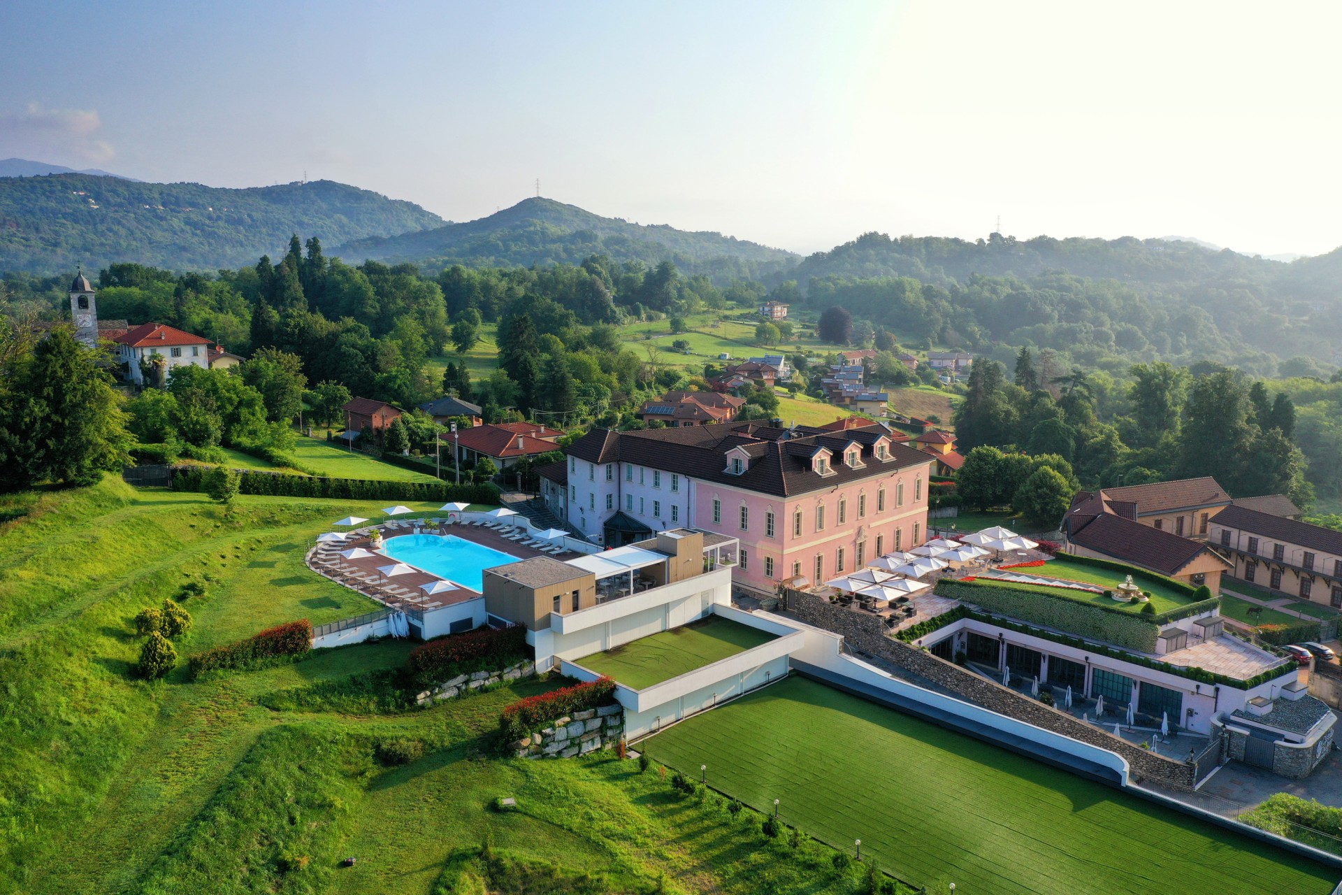 a large building with a pool in the middle of a green field