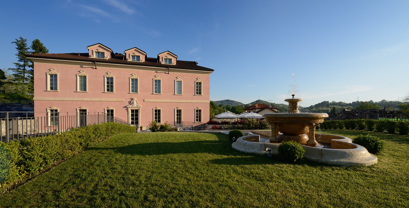 a fountain in front of a pink building