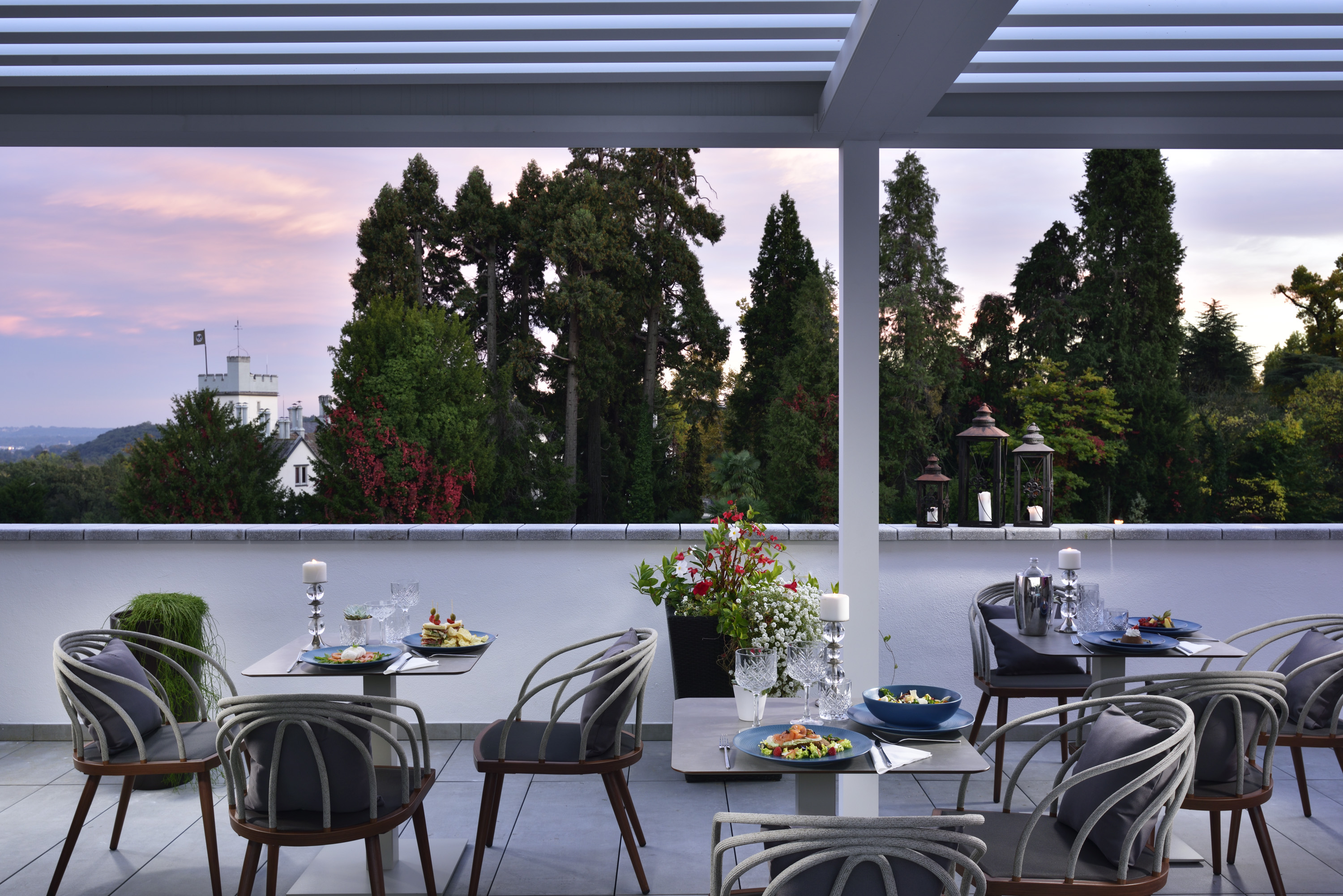 a table set up on a patio with a view of trees and a city