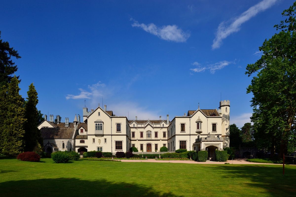 a large white building with a lawn and trees