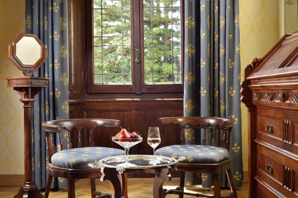 a table with fruit and a glass of wine in front of a window