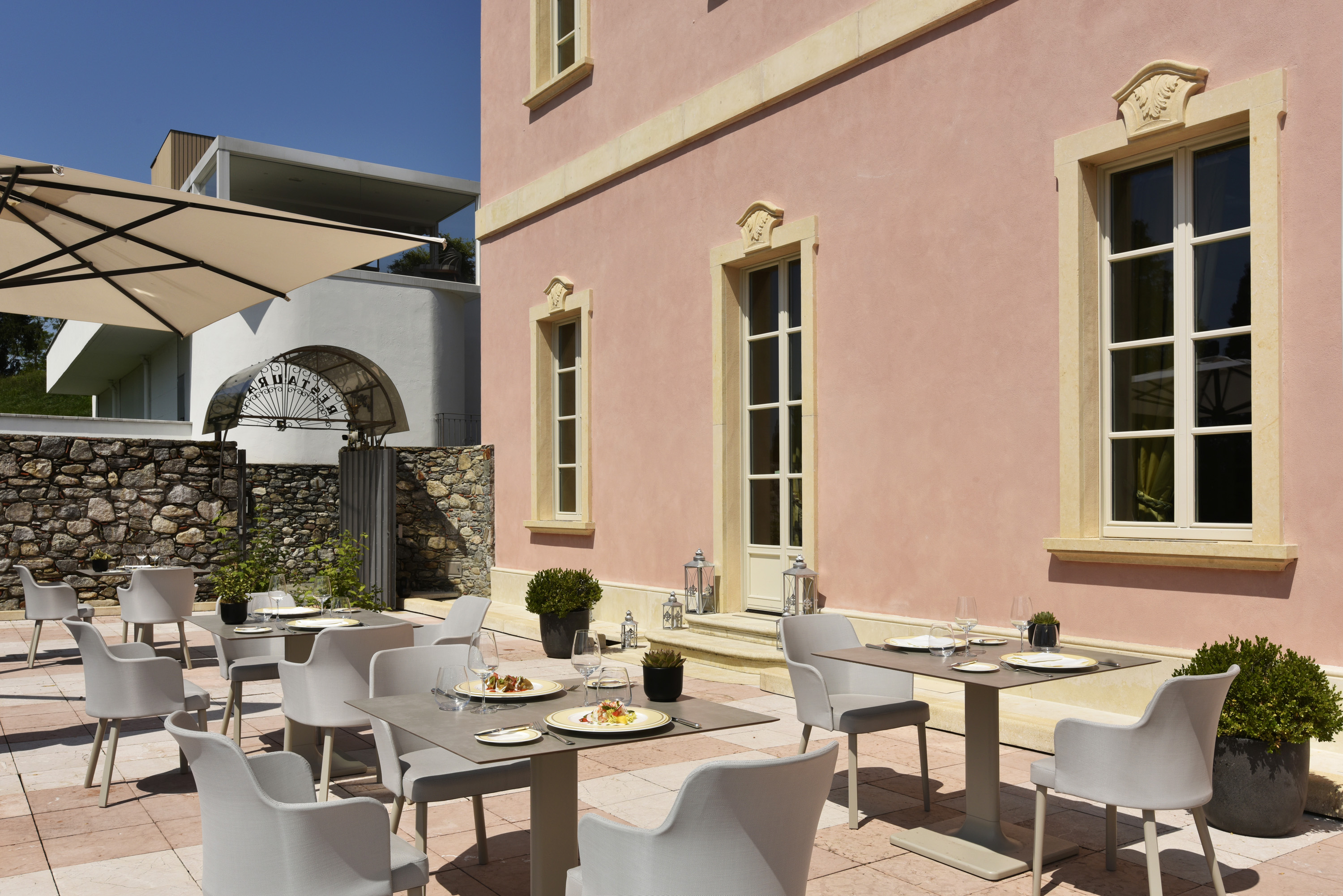 a table and chairs outside of a pink building
