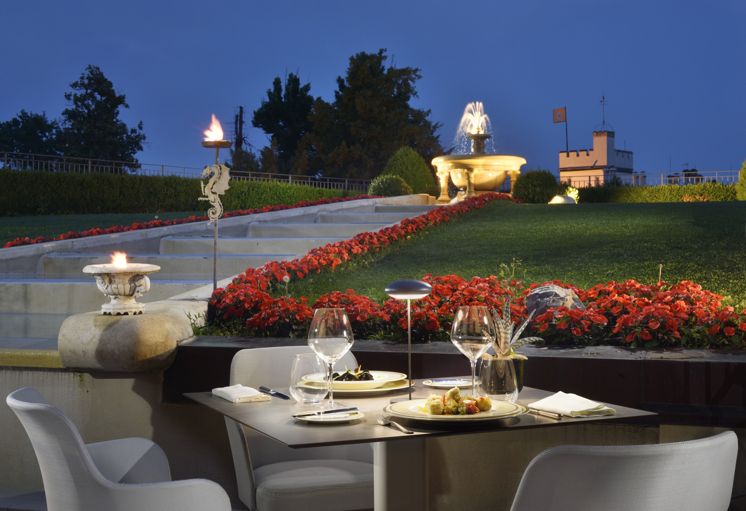 a table set up for a dinner with a fountain and flowers