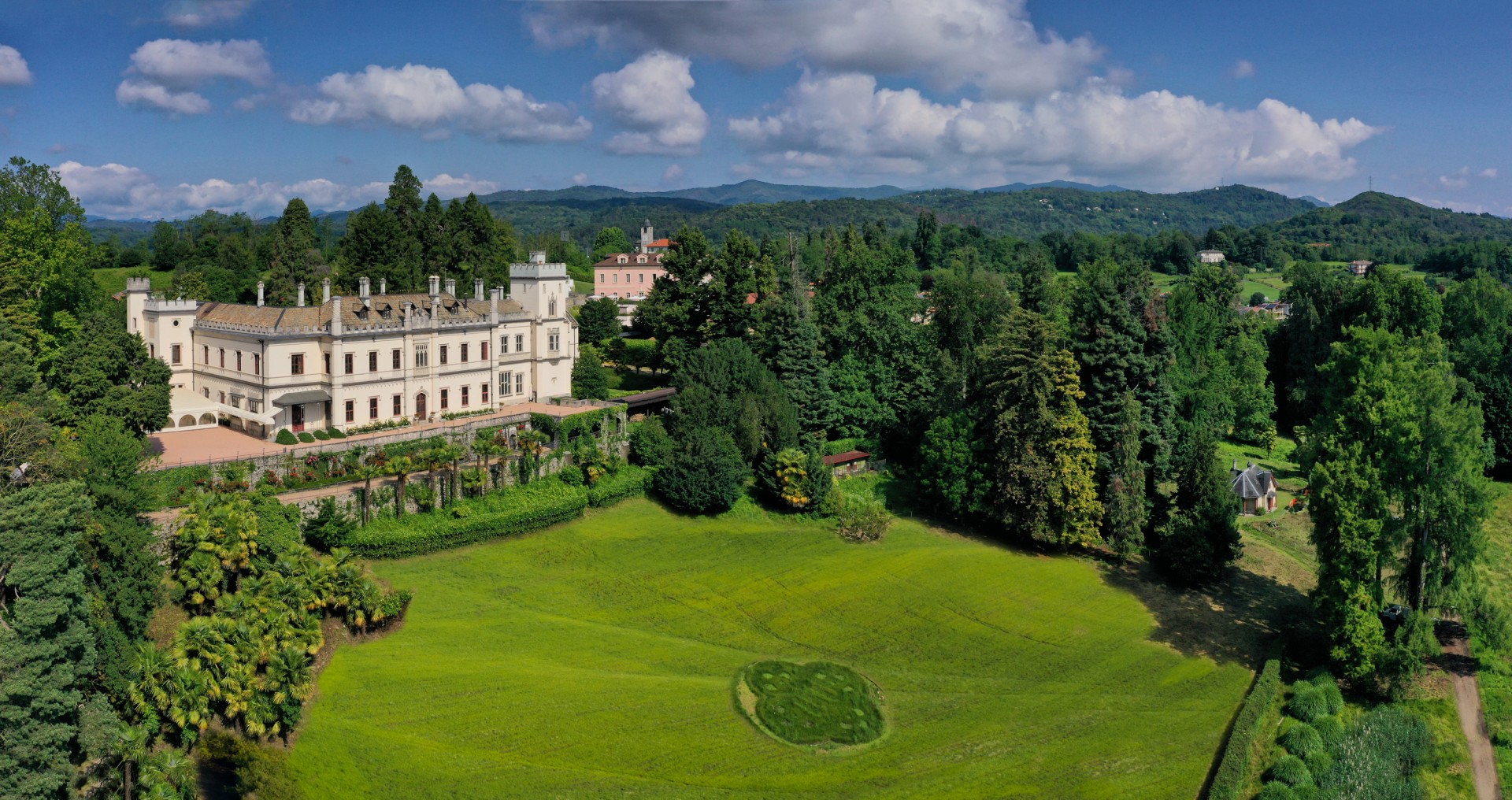a large lawn with trees and a building in the background
