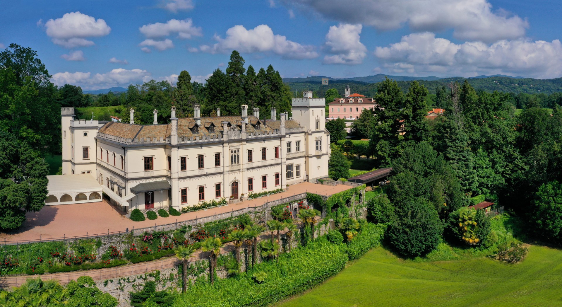 a large white building with a garden and trees