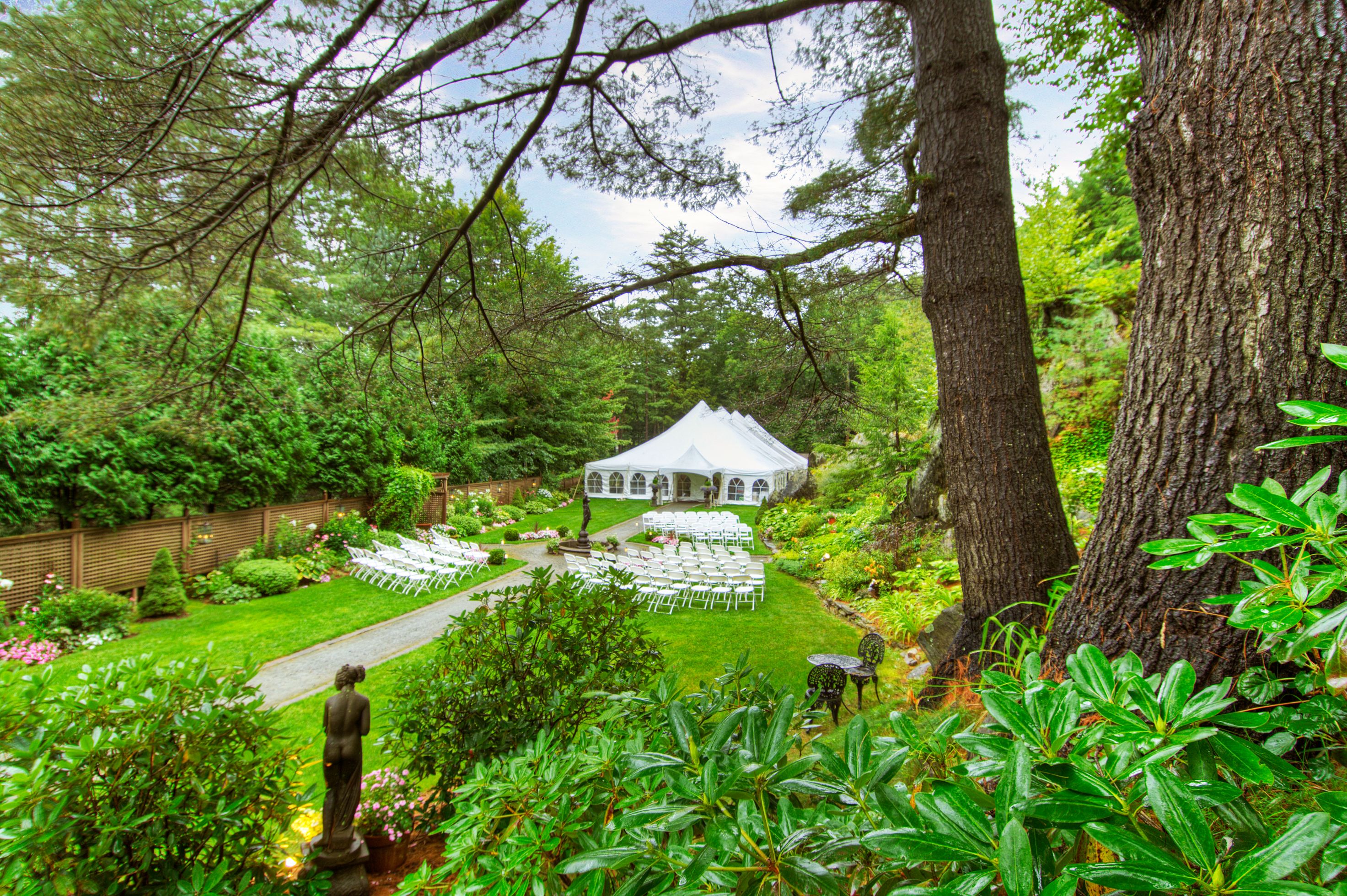 a white tent with chairs in the middle of a garden