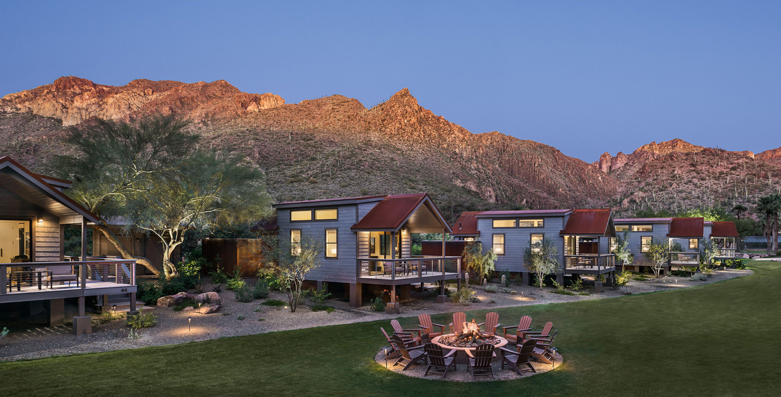 a group of houses with a fire pit in front of a mountain