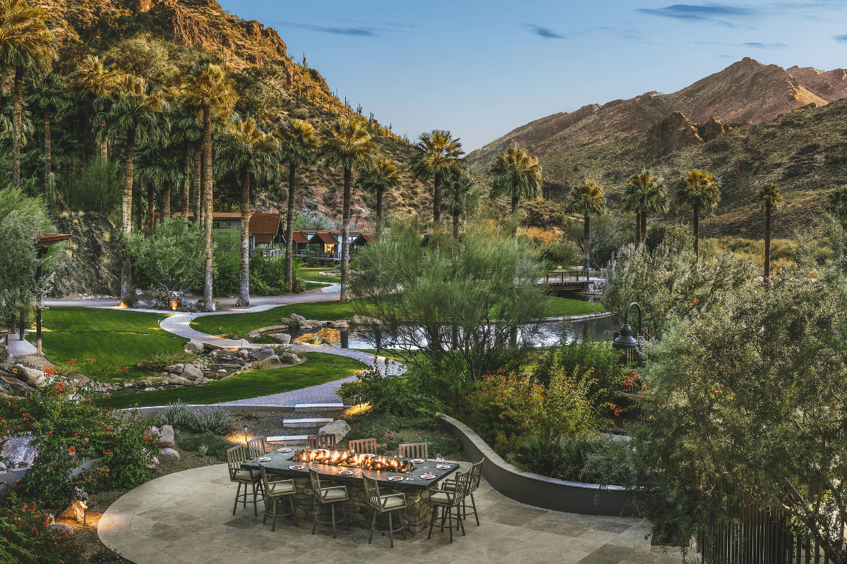 a table with candles on it surrounded by trees and a river