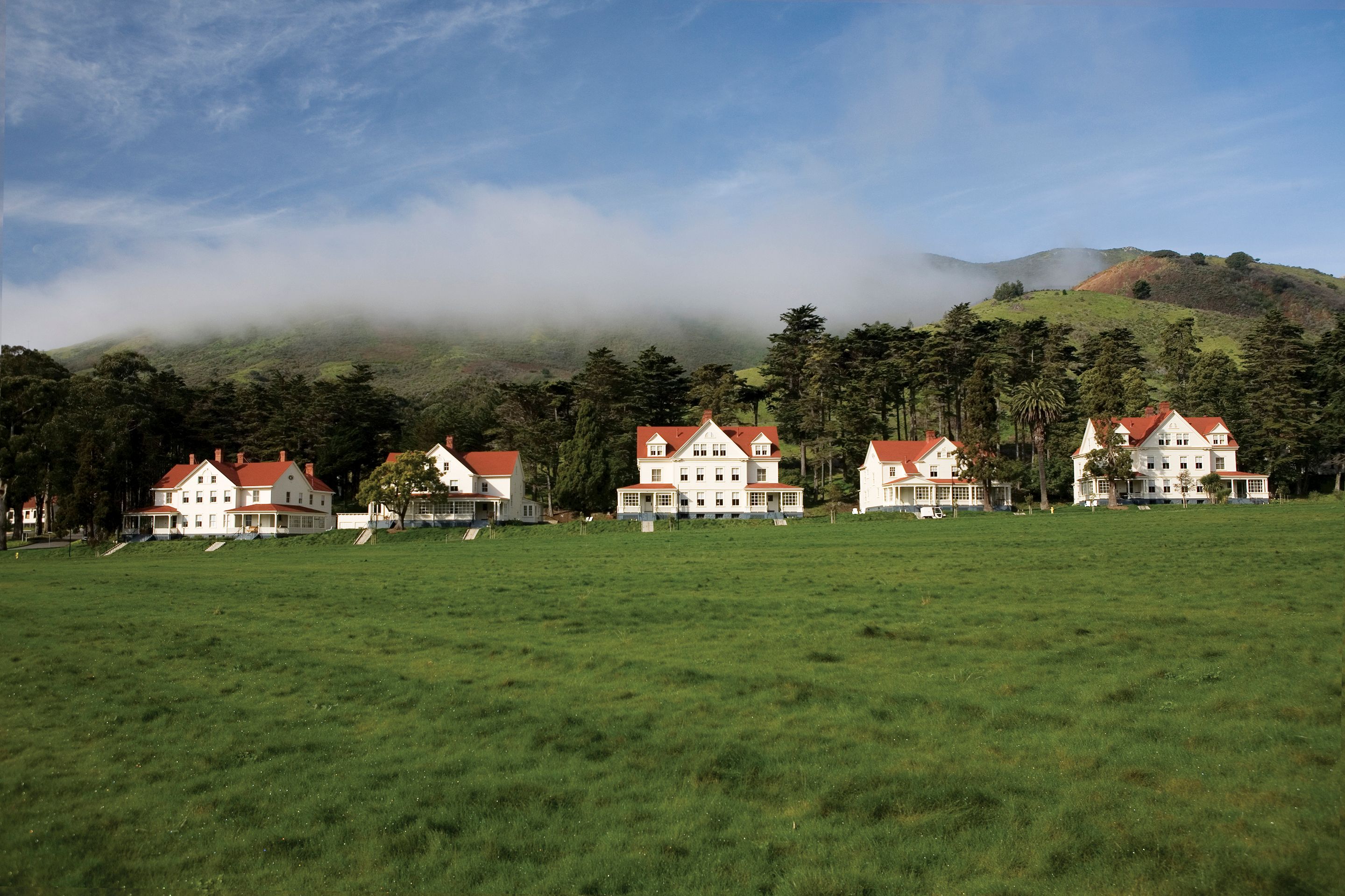 a group of houses in a large green field