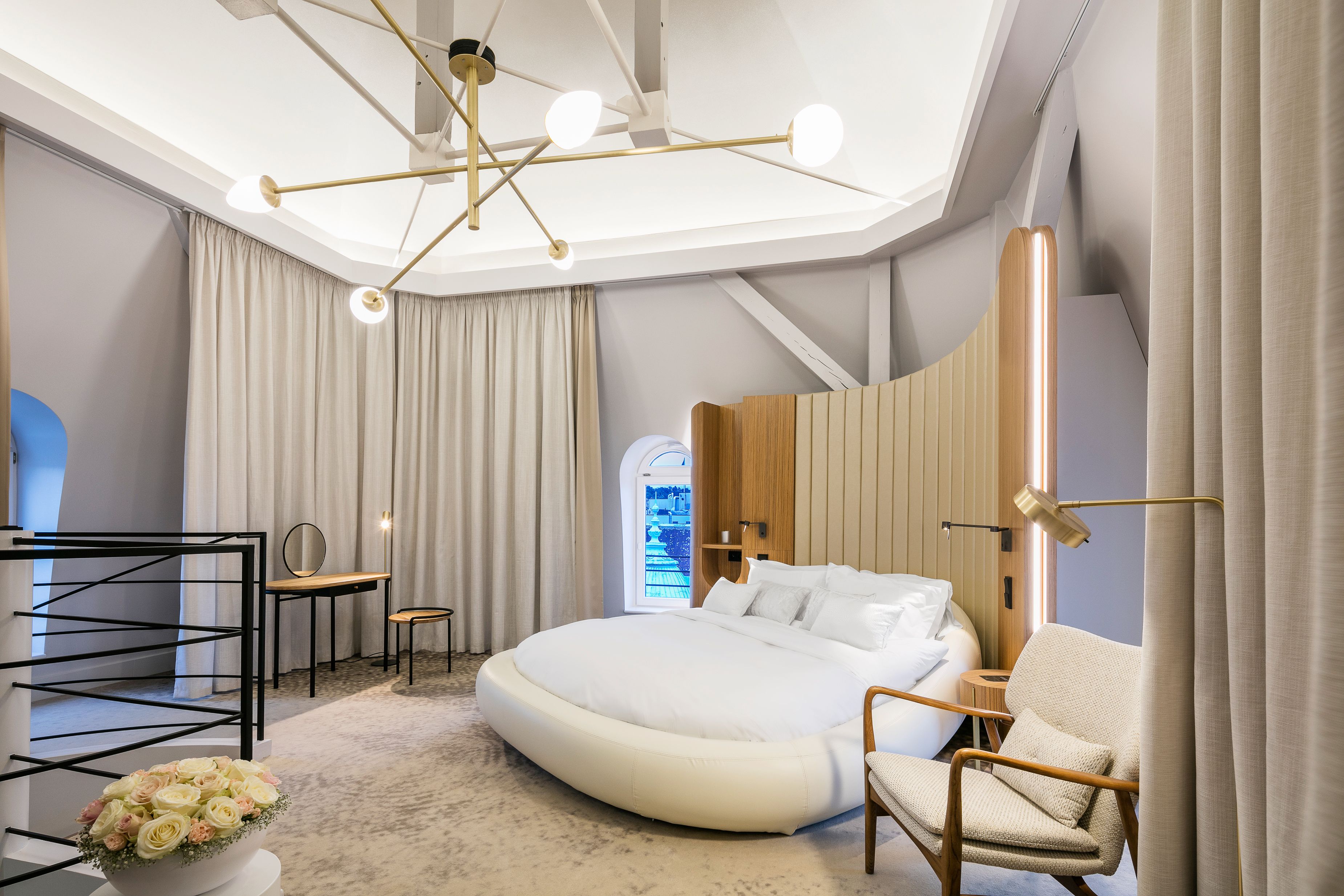 a bedroom with a round bed and chairs