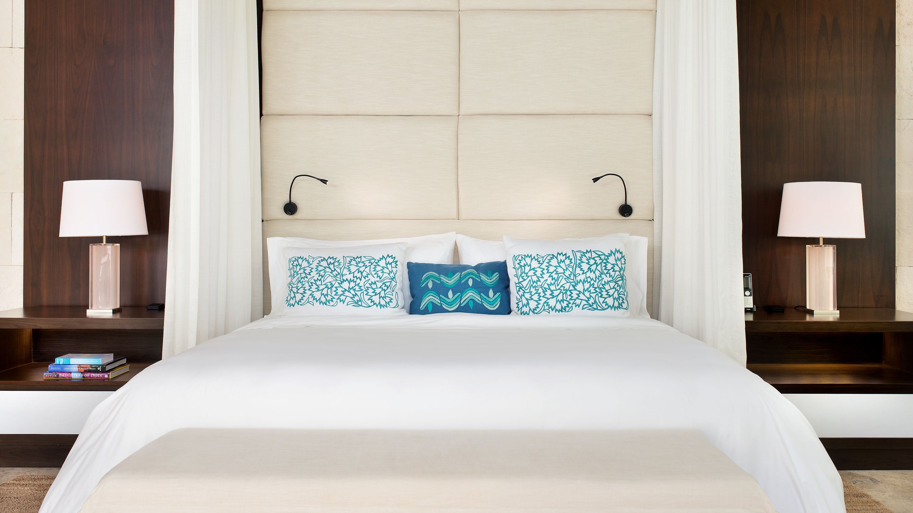 a bed with white sheets and blue pillows