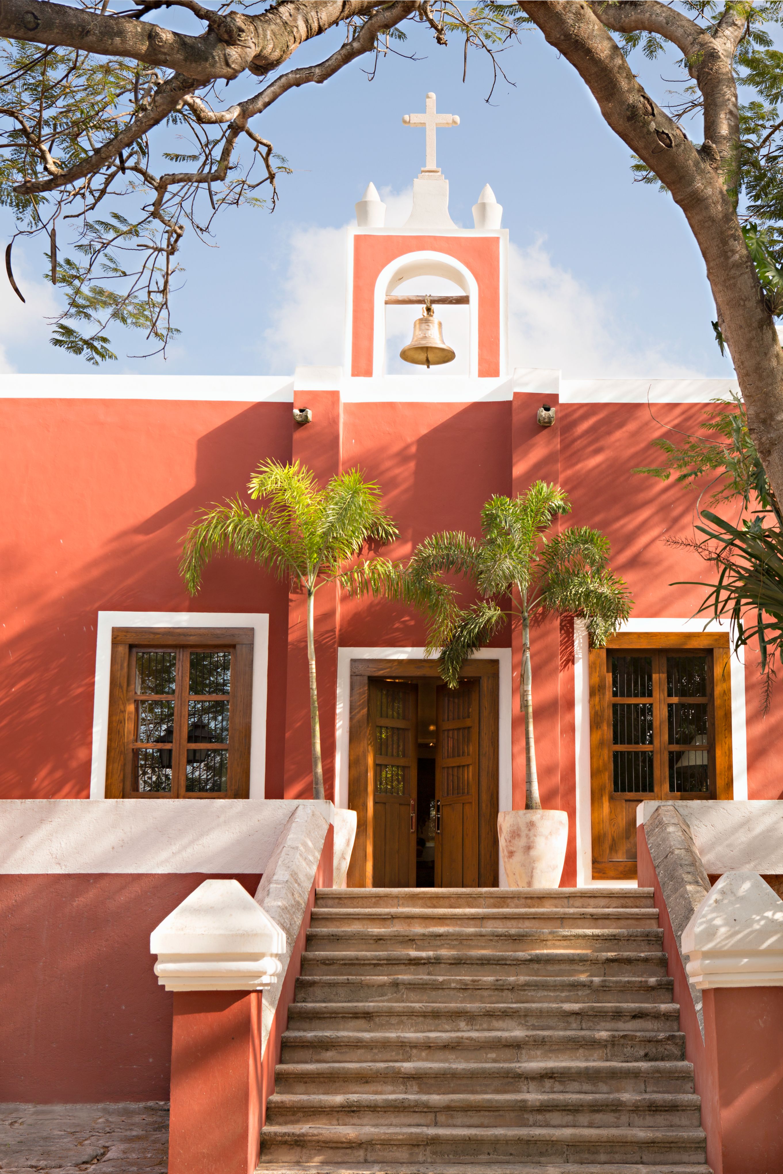 a red building with a bell tower and palm trees