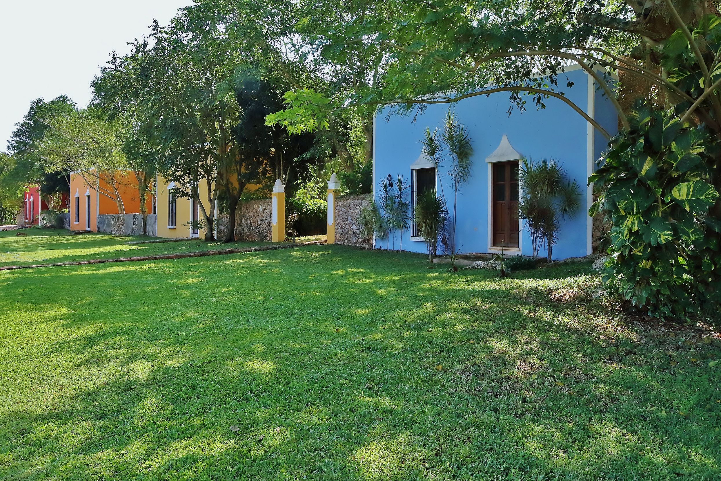 a blue and yellow building with a green lawn and trees