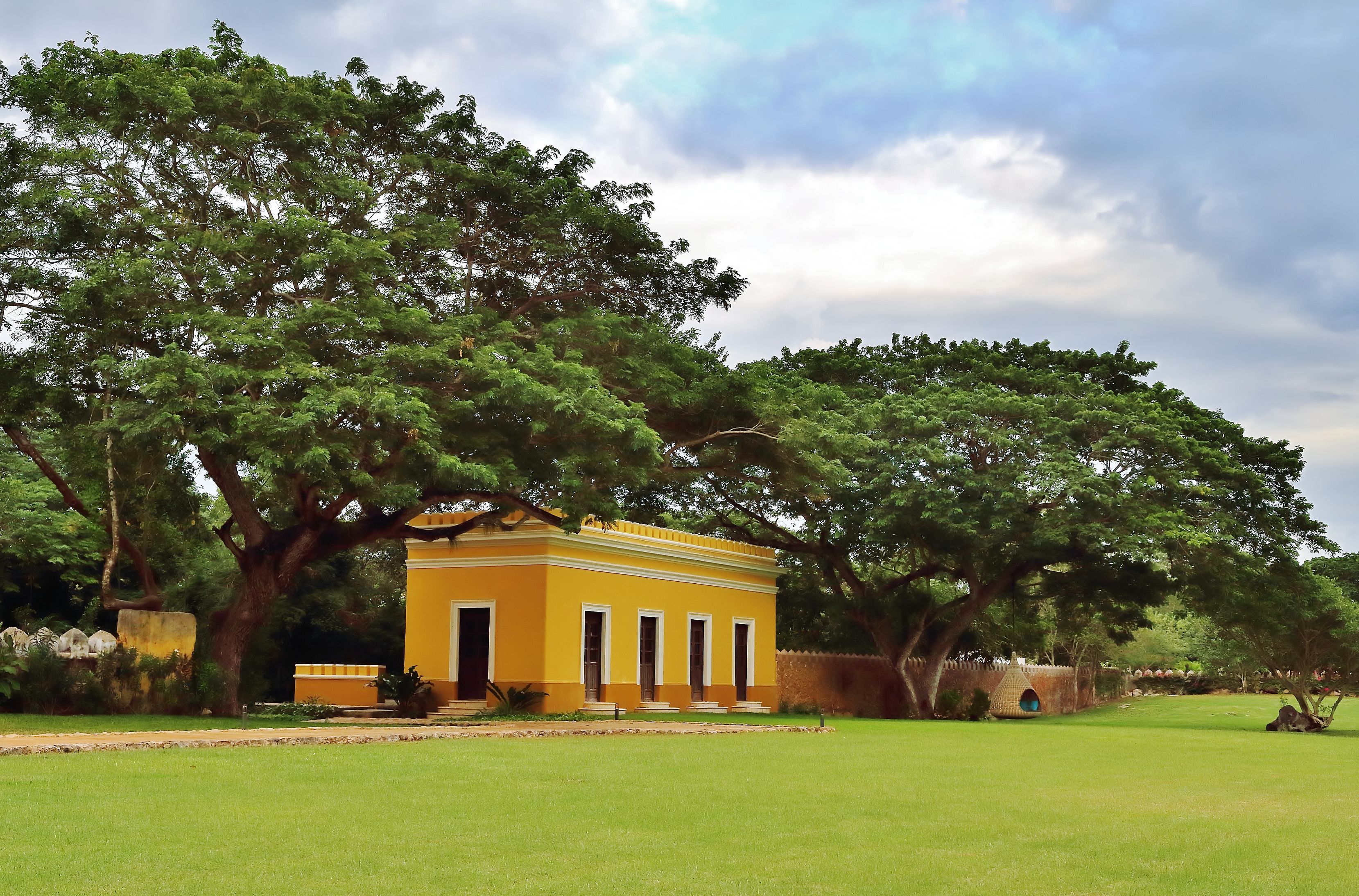 a yellow building with trees in the background