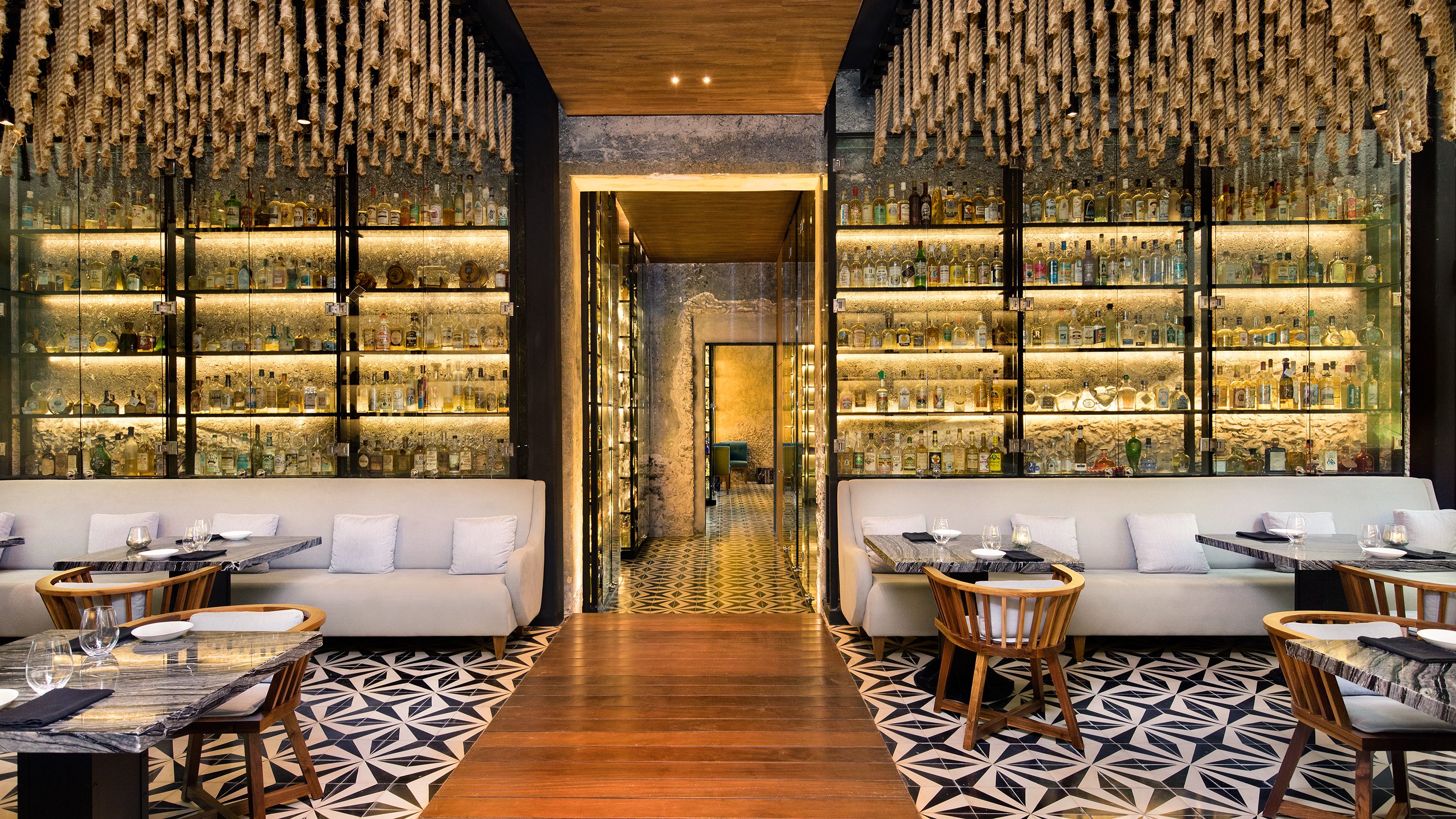 a room with a table and chairs and shelves with bottles