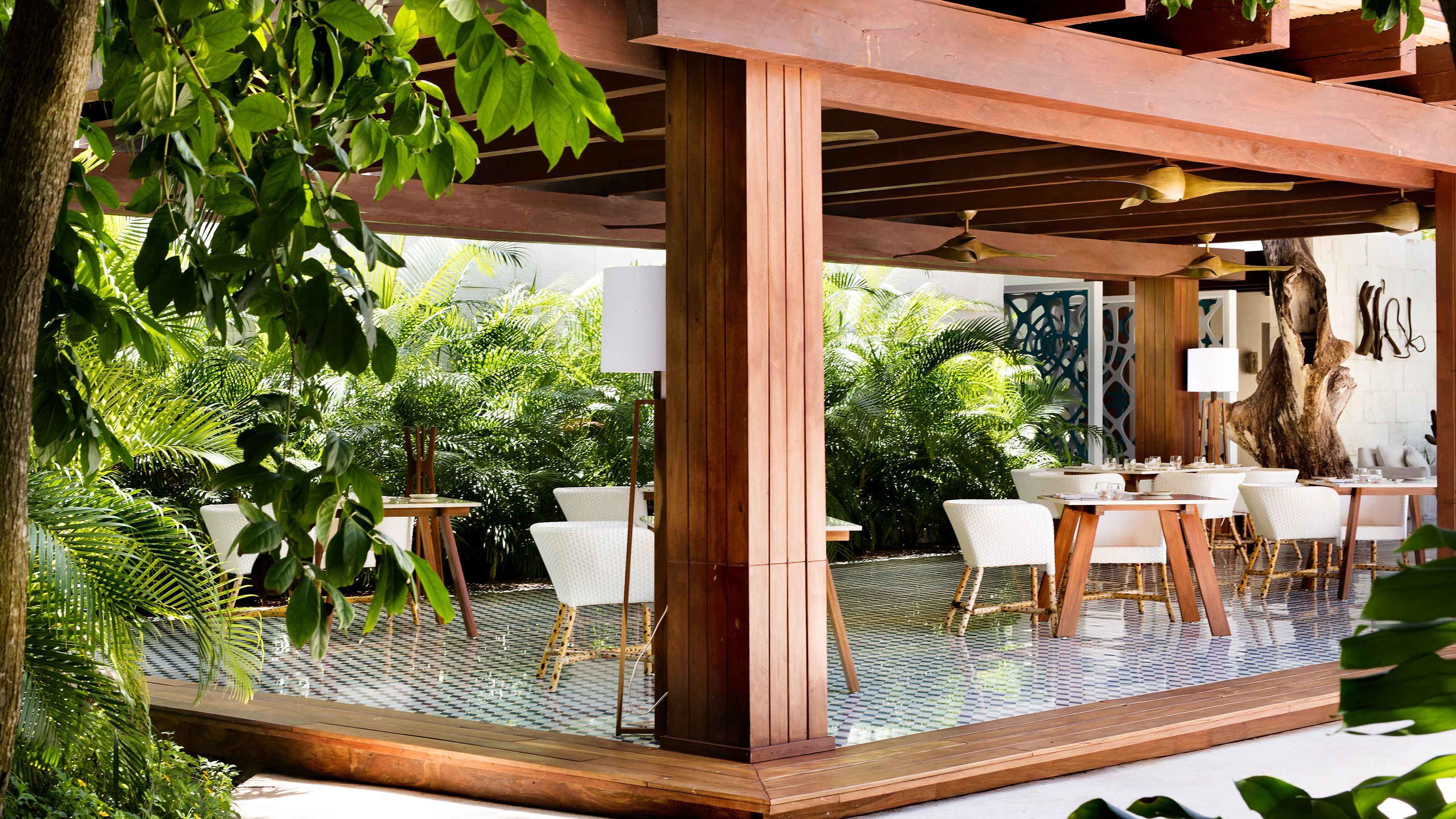 a wooden structure with tables and chairs under a covered patio
