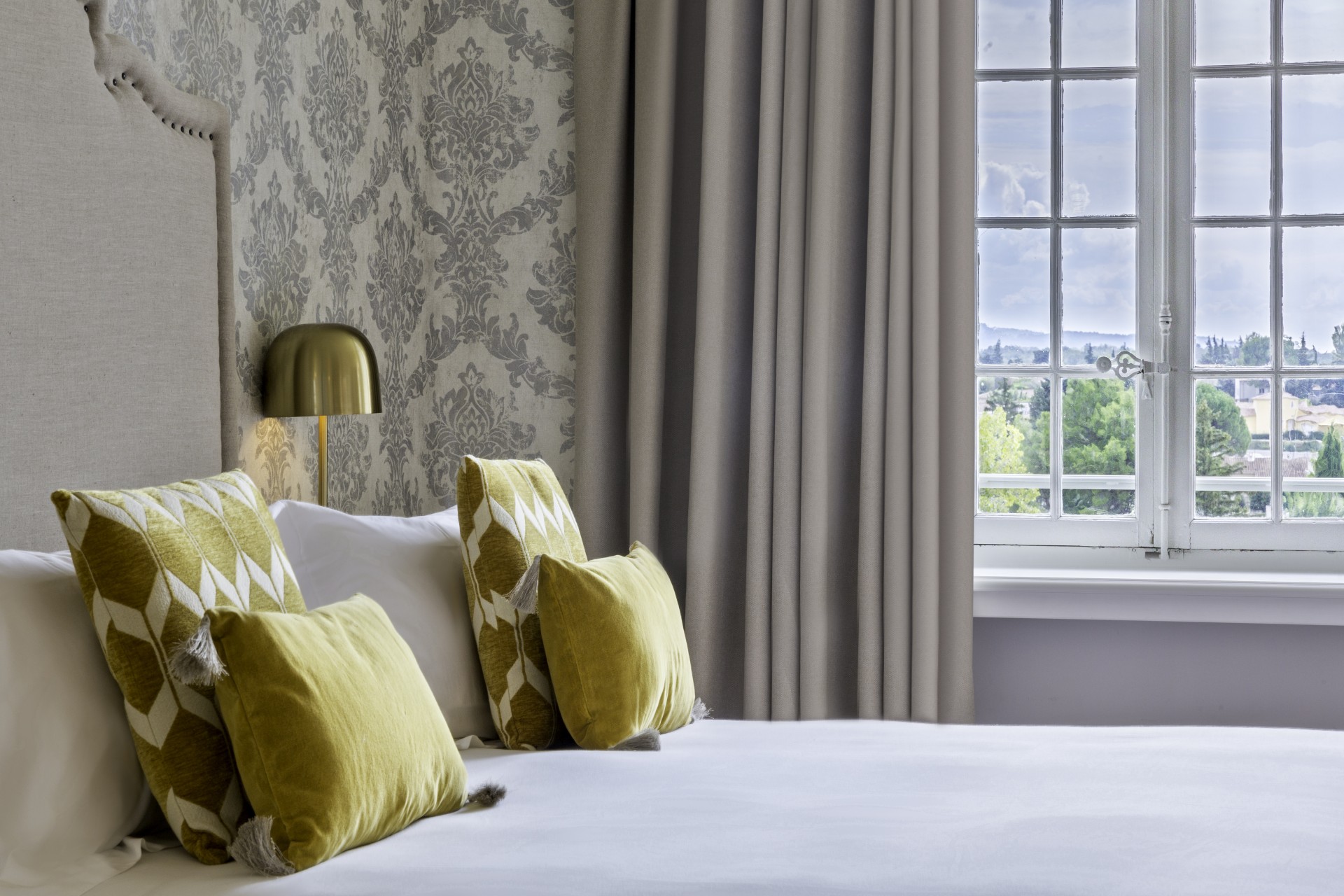 a bed with pillows and a lamp in a room with a window