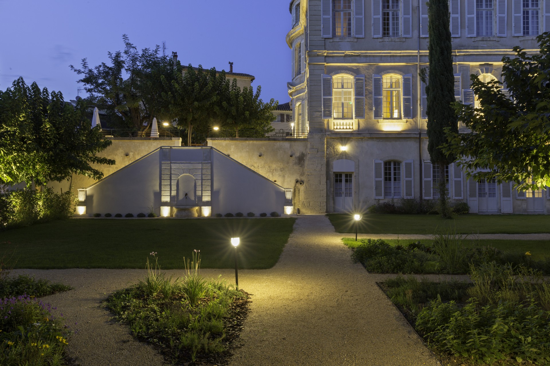 a walkway with lights on it and a building with trees and a staircase