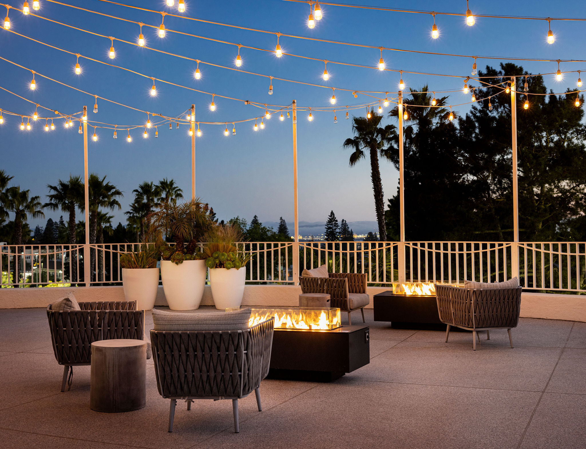 a patio with a fire pit and chairs and a white railing