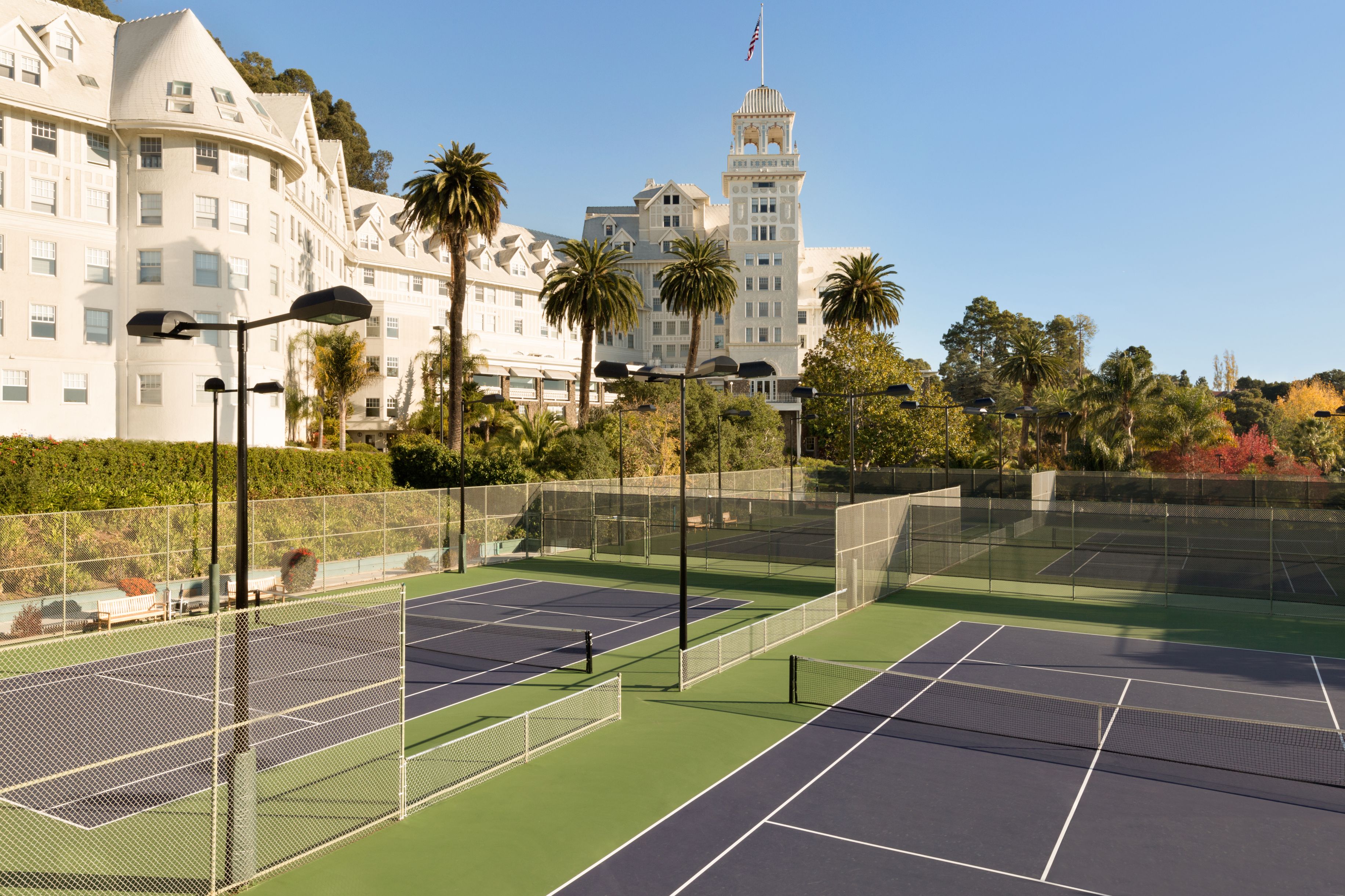 a tennis court with trees and a building in the background