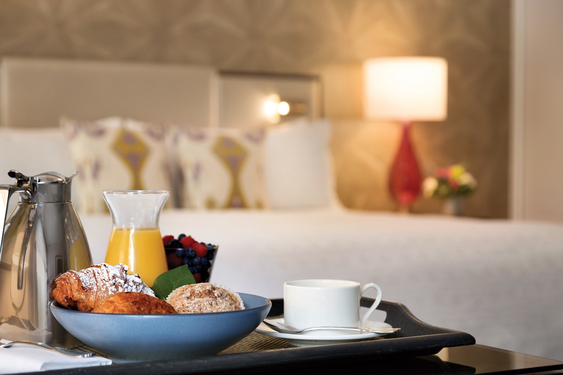 a tray with food and a cup of coffee in front of a bed