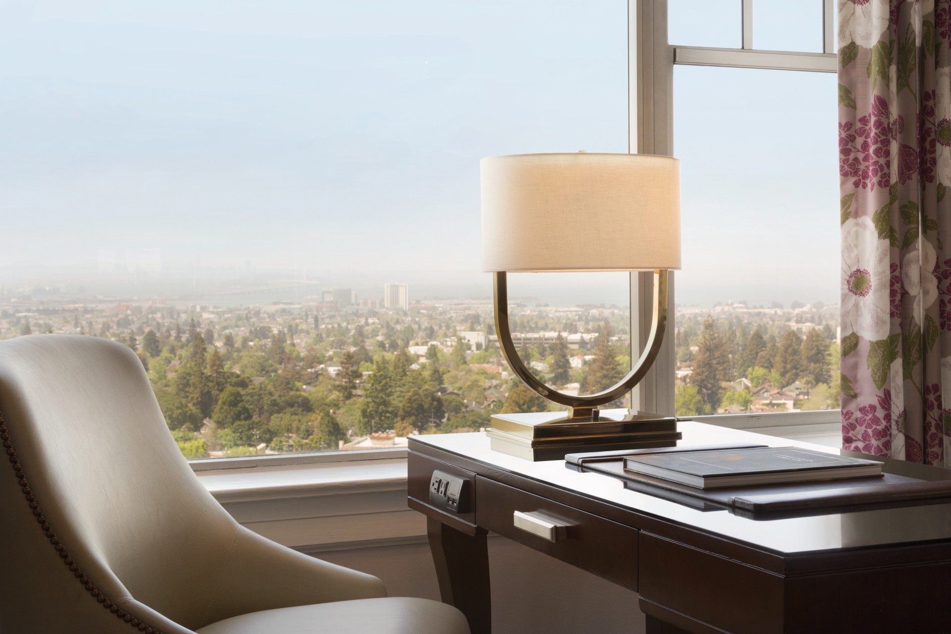 a desk with a lamp and a book in front of a window