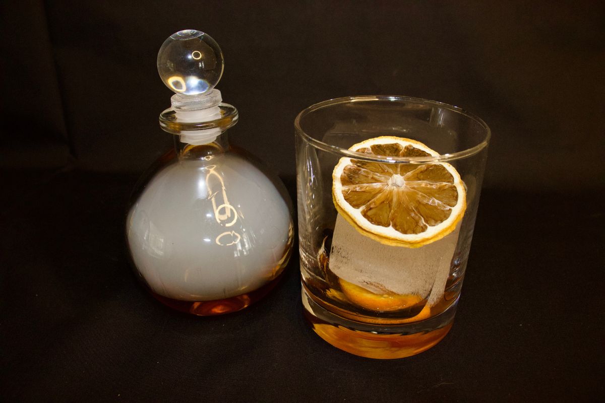 a glass with a slice of lemon in it next to a decanter